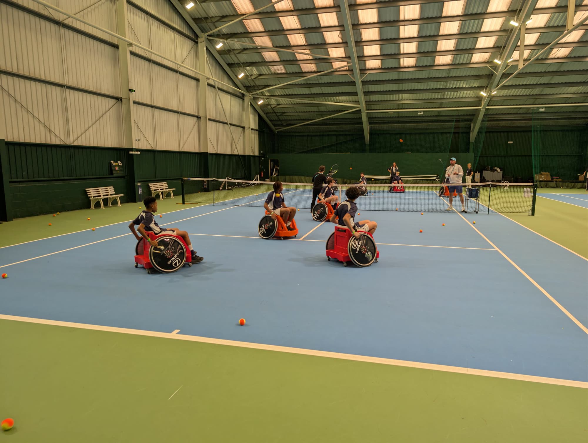 Children playing wheelchair tennis on an indoor court