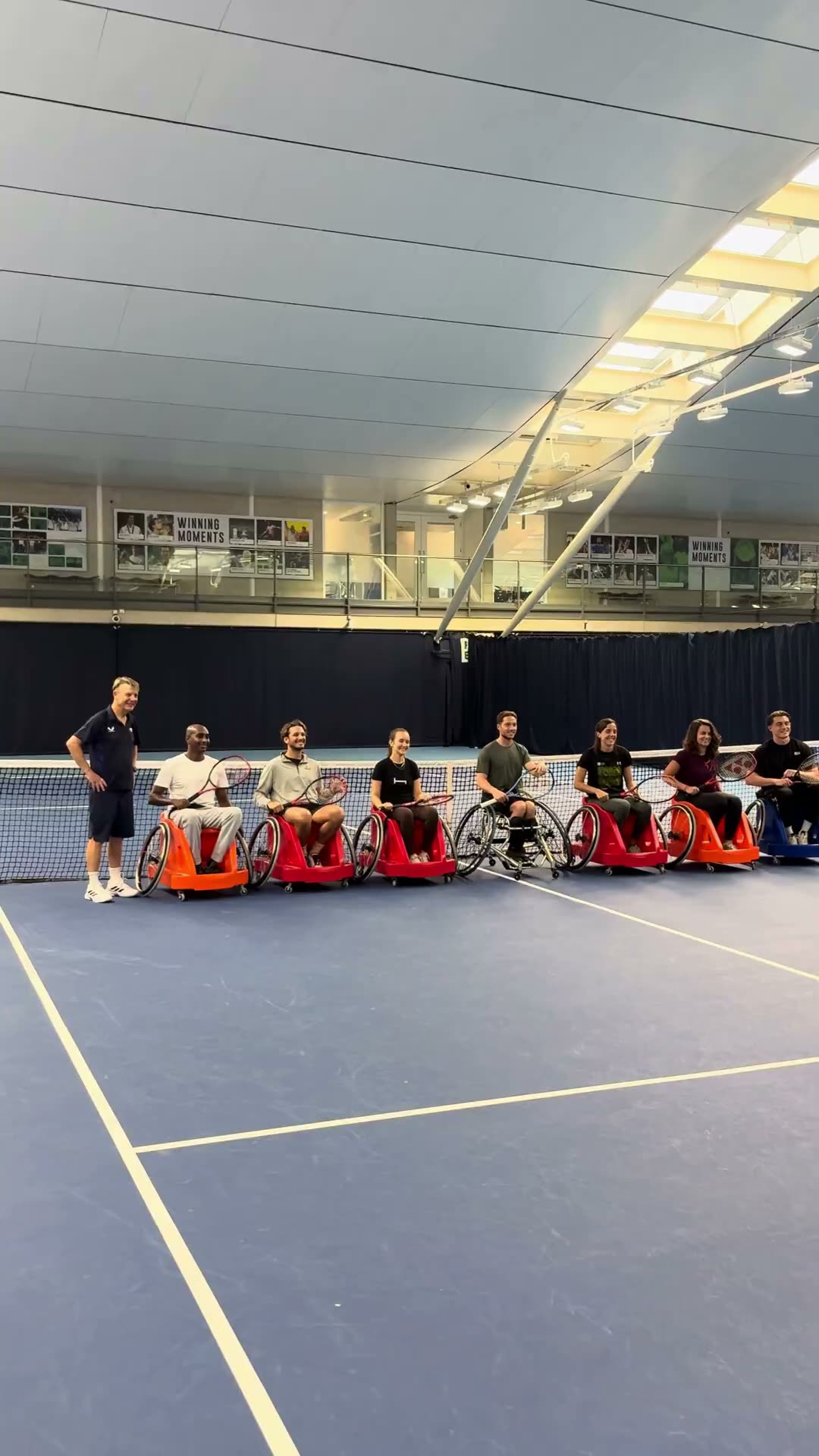 A group of players lined up in sport wheelchairs at the net