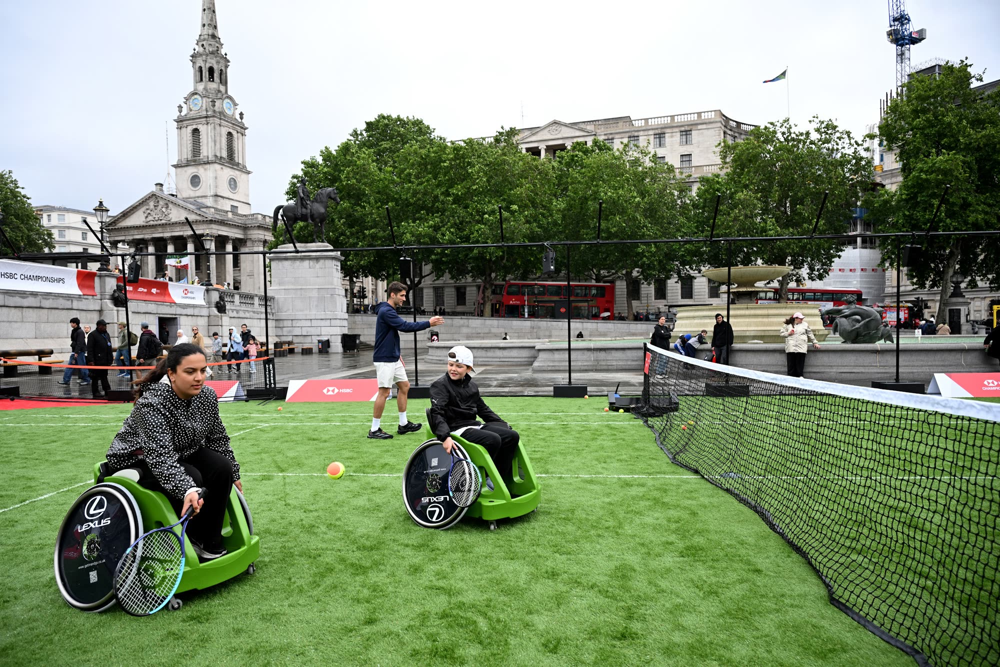 Wheelchair tennis being played on the grass court in Trafalgar Square, with St Martin-in-the-Fields behind