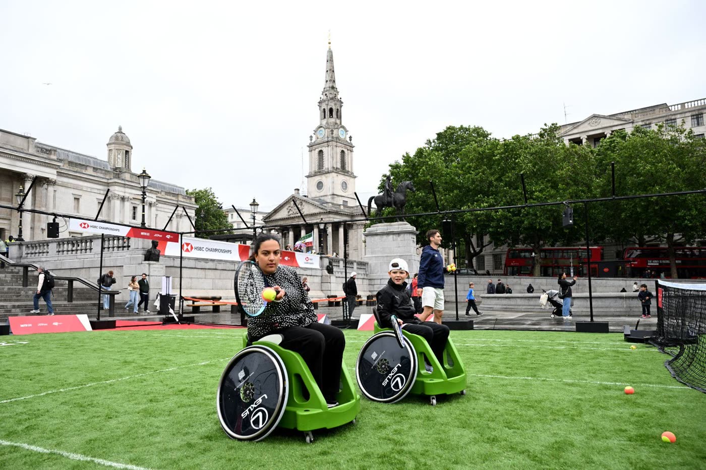 Two people playing wheelchair tennis on a grass court in Trafalgar Square