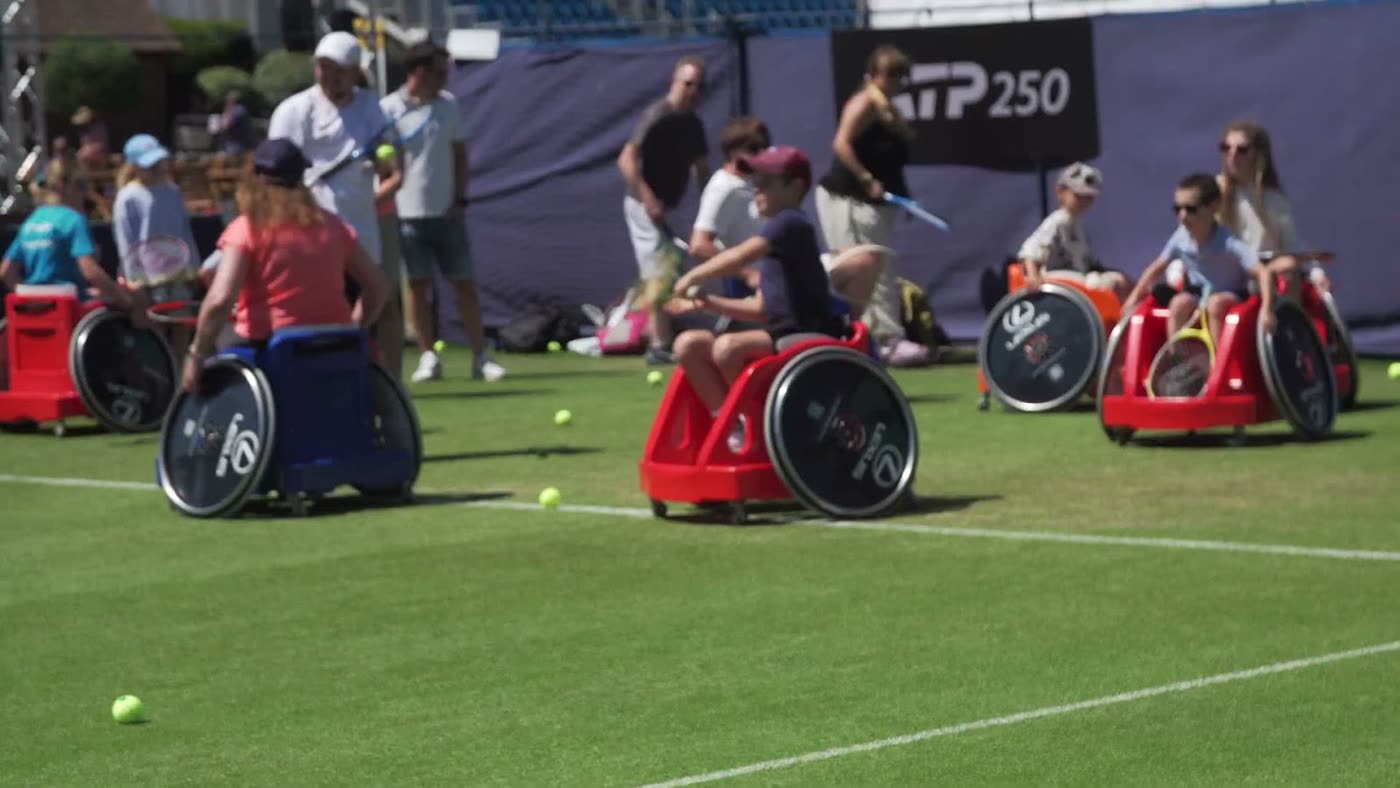 Children and adults in sport wheelchairs on a grass court